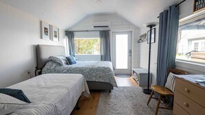 Un dormitorio con dos camas, un escritorio, una silla y una ventana con cortinas.