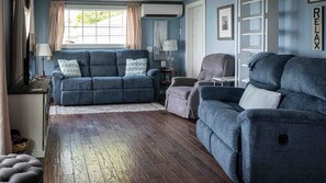 Una sala de estar con un sofá azul, un sillón gris y una alfombra estampada.