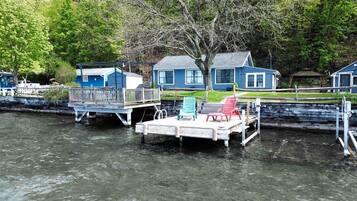 A dock with a boat, a small pier, and a house with a blue exterior.