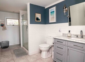 Een badkamer met een douchecabine van glas, een toilet en een wastafelmeubel met een wastafel.