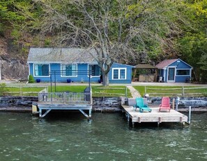 A dock with two houses, one with a blue exterior and another with a red exterior, connected by a wooden walkway.