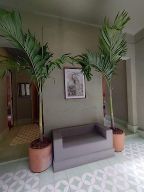Relax in a serene space with a bench, potted plants, and a beautiful artwork on the wall.