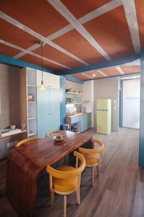 Cozy kitchen with central island and dining area, featuring a modern design with a wooden beam ceiling.