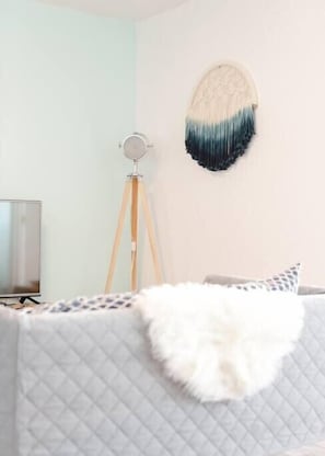 Relax in a serene space with a plush bed, round mirror, and wall decor.