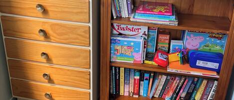 A bookshelf with children's books and a wooden dresser with drawers.