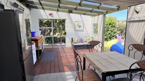 Un patio couvert comprenant une table et des chaises, un canapé et un réfrigérateur.