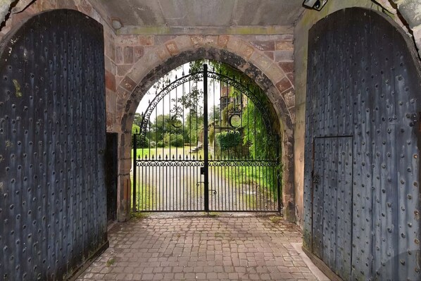 A gated entrance with a brick archway and a metal gate.