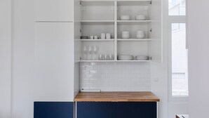 A kitchen with white cabinets, a wooden countertop, and a window.
