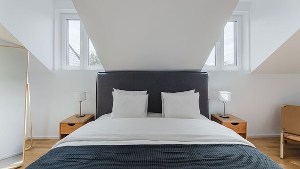 A modern bedroom with a large bed, two bedside tables, and a floor lamp.