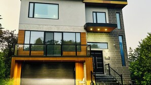 A modern two-story house with a garage, large windows, and a brick facade.