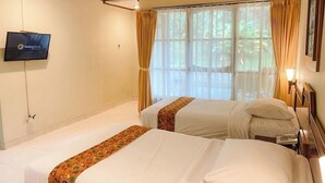 Habitació d'hotel amb dos llits, televisió i finestra amb cortines.