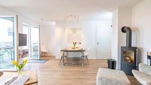 Een moderne woonkamer met een eethoek, een open haard en uitzicht door een glazen deur.