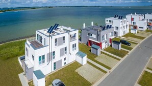 Een modern woongebied met witte gebouwen, zonnepanelen en een auto op de oprit.