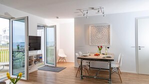Een moderne woonkamer met een eethoek, een televisie en een balkon met uitzicht.
