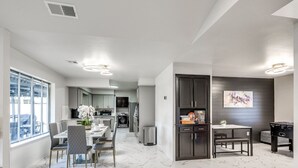 A modern kitchen with marble flooring, a dining area with a table and chairs, and a living area with a pool table.