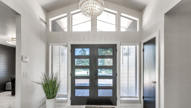 A spacious entrance with a double door, a potted plant, and a marble floor.