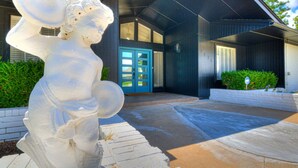 A modern building with a blue door, a white statue, and a clear sky.