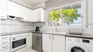 A modern kitchen with white cabinets, a built-in oven, dishwasher, and washing machine. - WELCS APARTAMENTO 170 PDA en el puerto (Platja d´Aro)