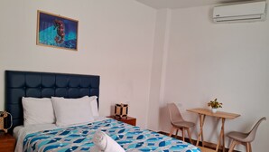 A hotel room with a large bed, a small table with a chair, a wall-mounted air conditioner, and a painting on the wall. - Hab21 Hotel in front of the sea, ideal to enjoy the sun and relax with Wifi and AC (Canoas de Punta Sal)