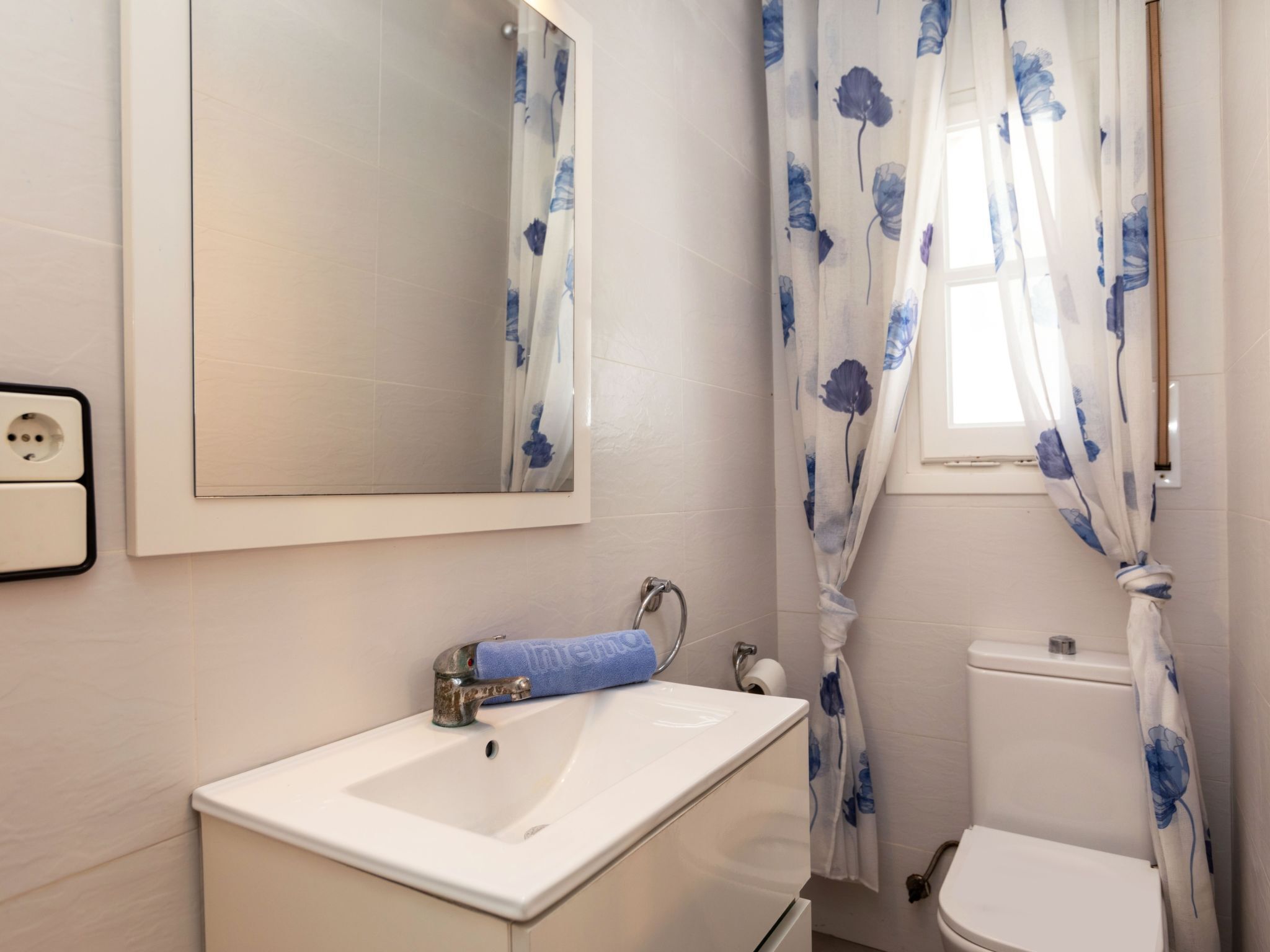 A bathroom with a white sink, mirror, and toilet.