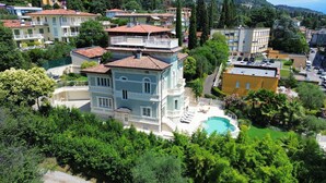 A multi-story building with a pool, surrounded by lush greenery and other residential buildings. - Villa Diamante By Bookinggardalake (Salò)