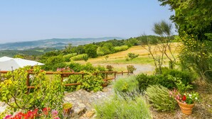 A garden with a stone pathway, a wooden fence, and a view of rolling hills and distant mountains. - Bellavista by Interhome (Castellina Marittima)