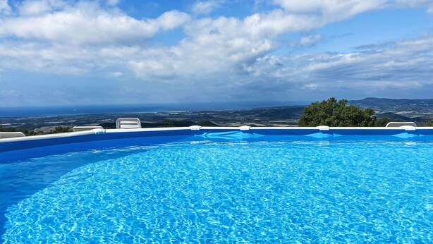 A clear blue pool with a view of the landscape and distant horizon. - Bellavista by Interhome (Castellina Marittima)