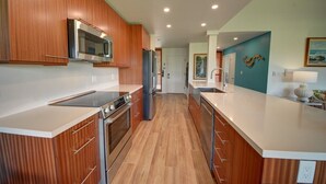 Una cocina moderna con armarios de madera, electrodomésticos de acero inoxidable y una isla central.