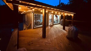 A wooden deck with a pergola overhead, connected to a building with glass doors and windows. - Waterfront Cozy Unit Bay St Louis / kayaks &dock (Bay St. Louis)