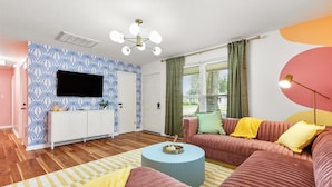 Un saló modern amb un sofà, una televisió, una taula de centre rodona i una paret amb un disseny decoratiu.
