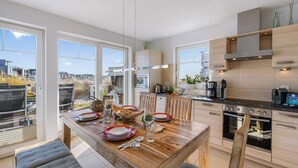 Une cuisine moderne avec un coin repas, de grandes fenêtres et une vue sur l’extérieur.