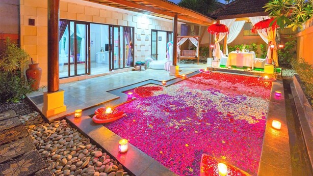 Un hôtel doté d’un espace extérieur abrité, agrémenté d’un sol décoré de fleurs, d’une piscine et d’un espace repas aménagé avec des parasols.