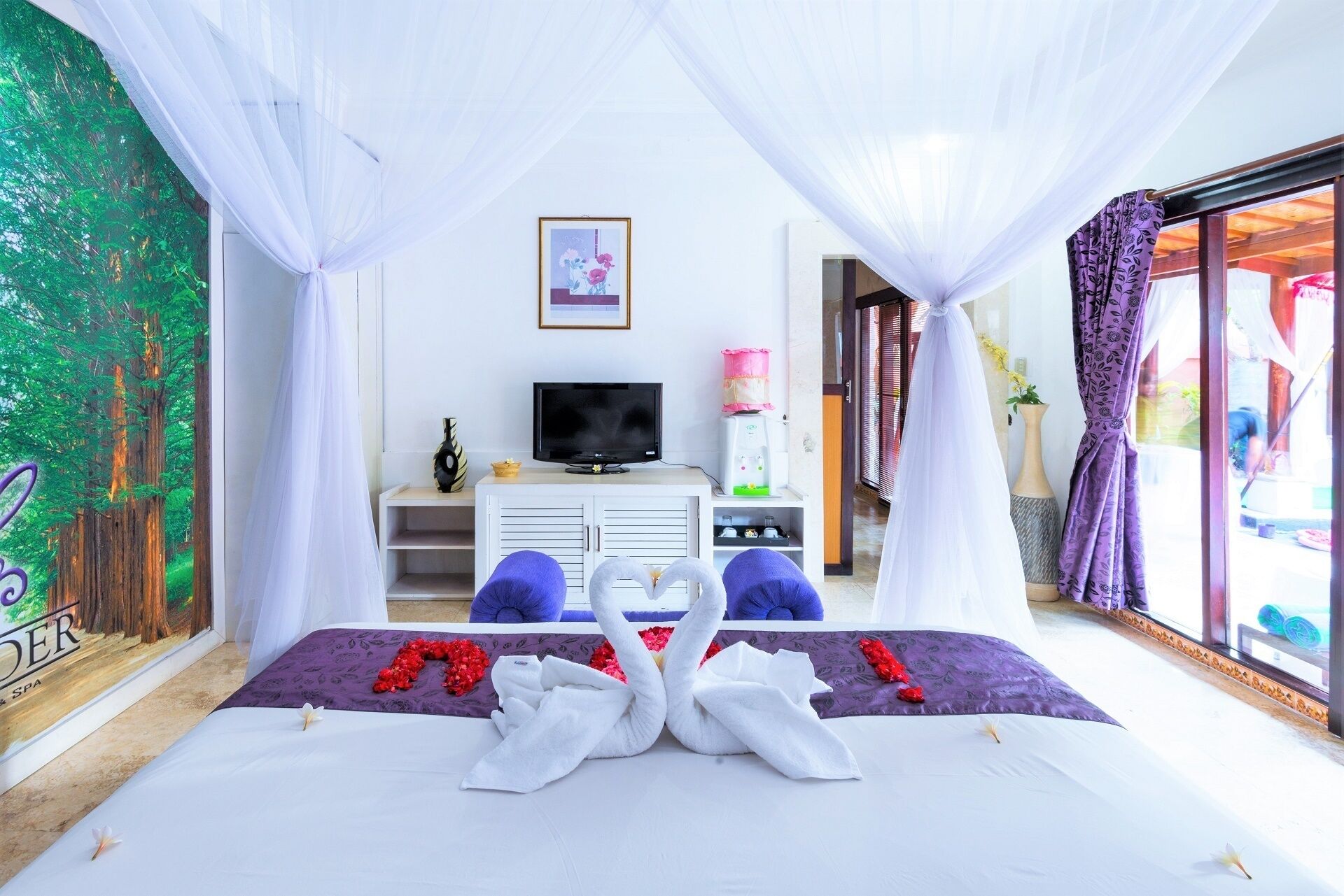 A bedroom with a bed, a TV, a water dispenser, and a view of the outdoors.