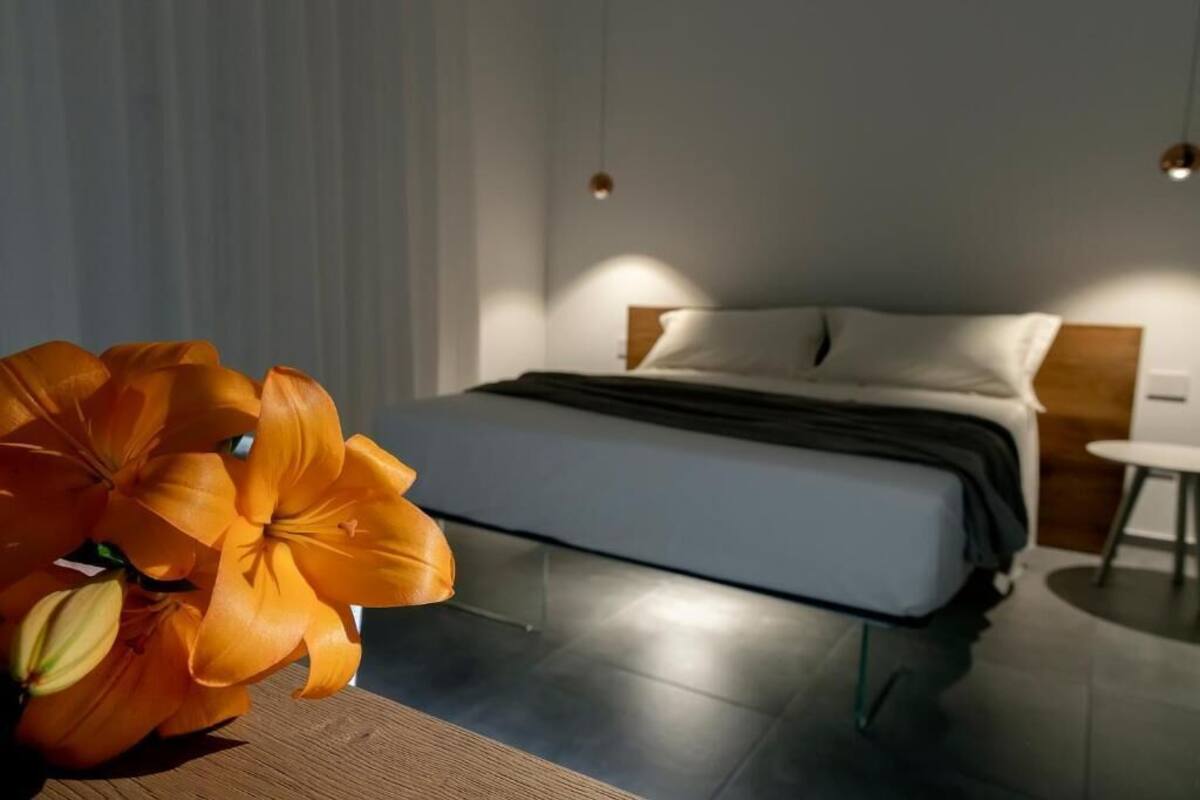 Un dormitorio moderno con cama, mesitas de noche y una mesita auxiliar de madera.