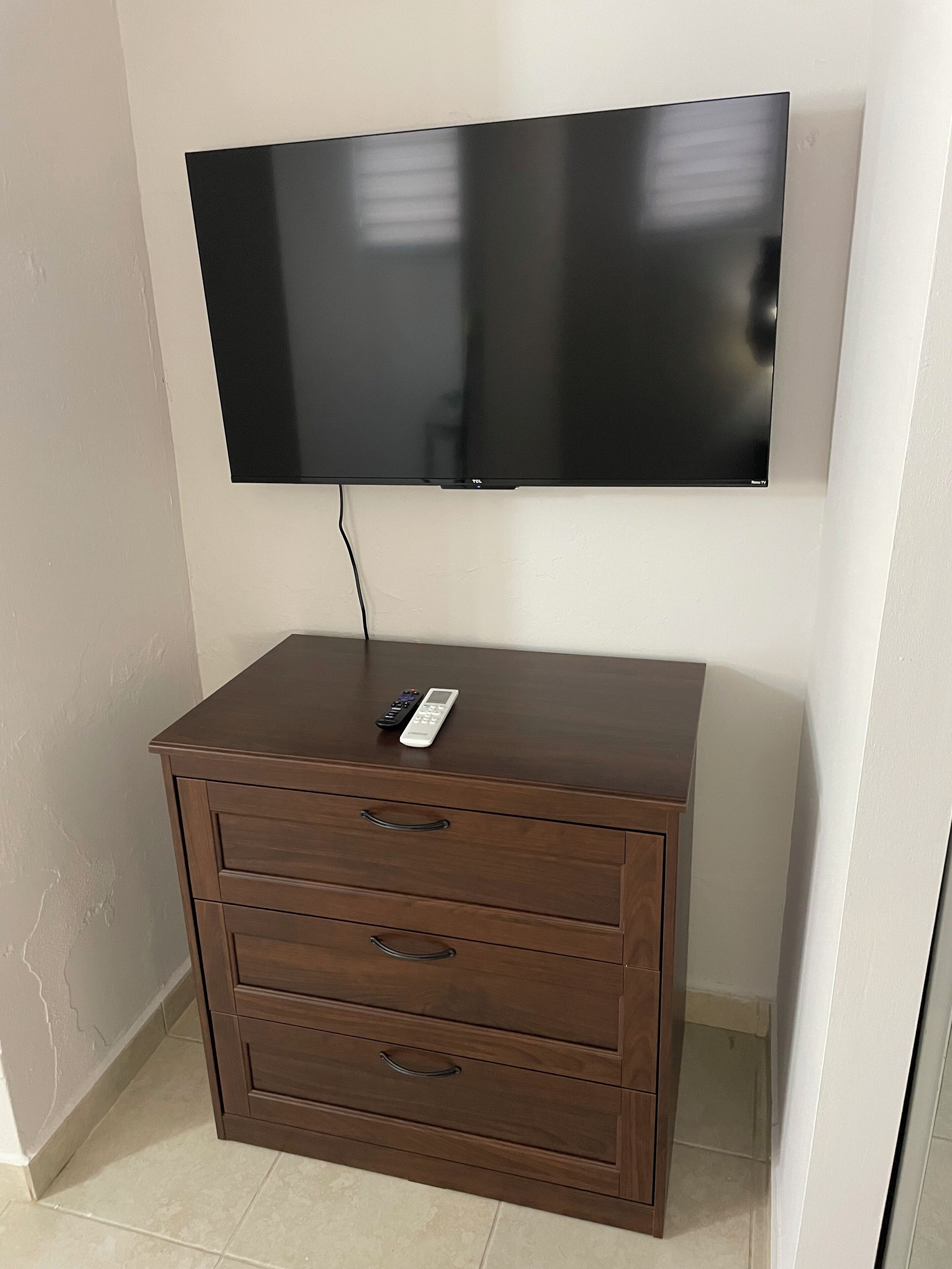Un televisor de pantalla plana montado en la pared sobre un mueble de madera con cajones.