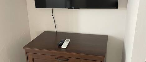 Un televisor de pantalla plana montado en la pared sobre un mueble de madera con cajones.