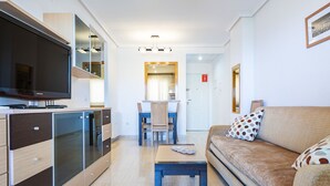 Ein modernes Wohnzimmer mit Flachbildfernseher, einer Couch, einem Couchtisch und einem Essbereich mit Tisch und Stühlen.