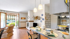 A kitchen with a dining area, a view through the glass door, and a dining table set with plates and bowls. - Appartamento Alessandra: Terrace and Lake View, Laveno Mombello, Italy (Laveno Mombello)