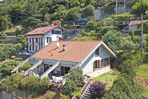A house with a sloped roof, a balcony, and a garden area with outdoor furniture.