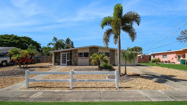 A single-story building with a stone facade, a front porch, and a palm tree. - Canal-Front Escape with Private Pool & Game Room in Port Charlotte - Point Of Rocks (Port Charlotte)