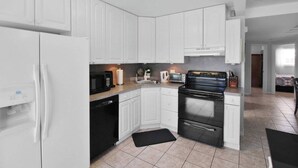 A modern kitchen with white cabinets, a black stove, and a dishwasher. - Canal-Front Escape with Private Pool & Game Room in Port Charlotte - Point Of Rocks (Port Charlotte)