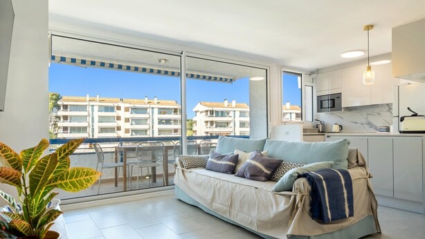 A modern apartment with a balcony, a sofa, a dining area, and a kitchen. - Apartment 250m beach with pool and parking (Torredembarra)