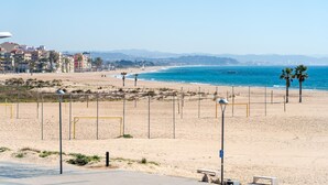 A beach with a clear view of the sea, a sandy shore, and a cityscape in the background. - Apartment 250m beach with pool and parking (Torredembarra)