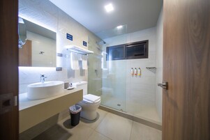 Un baño moderno con lavabo, inodoro y ducha con mampara de vidrio.