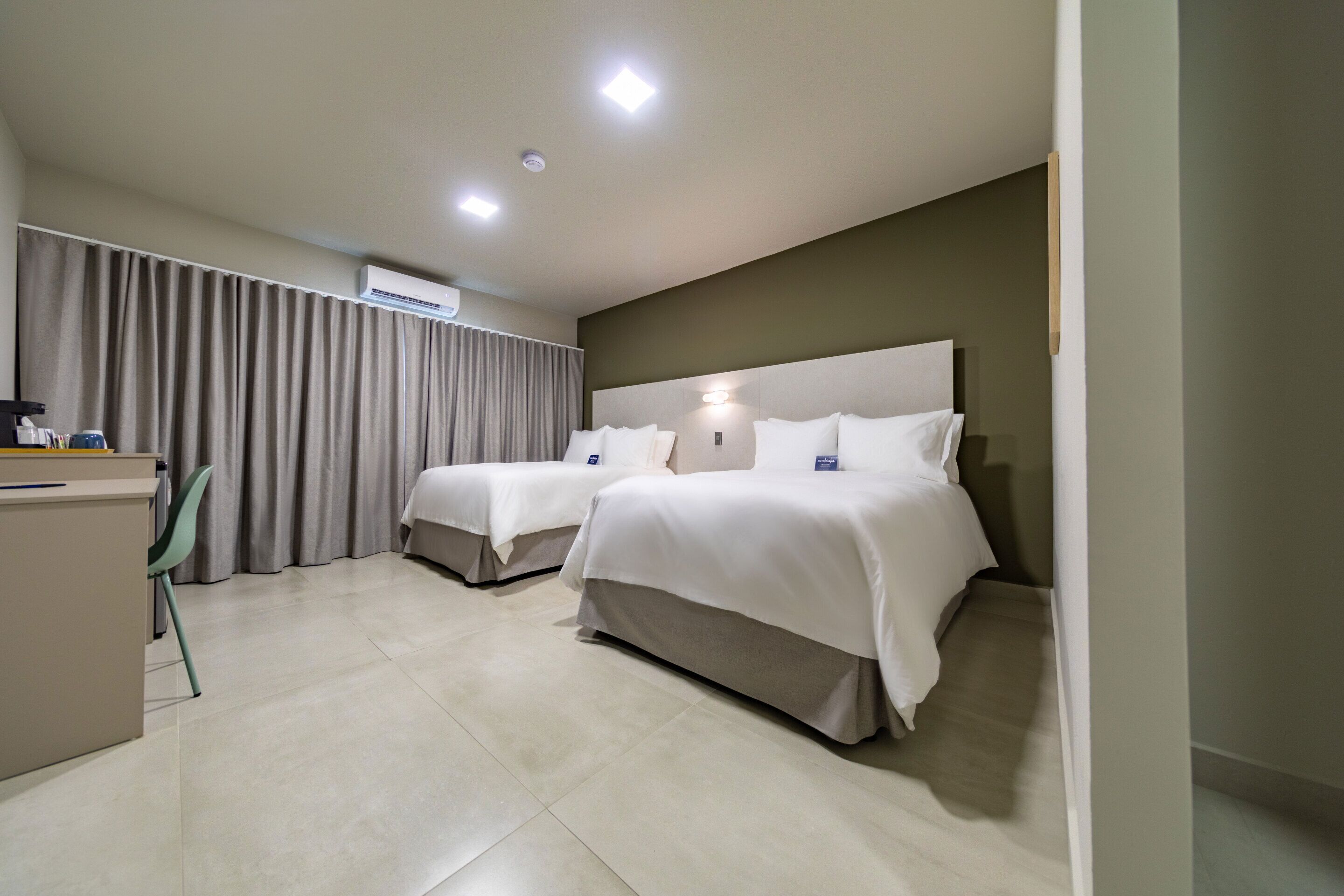 Una habitación de hotel con dos camas, un escritorio, una silla y un equipo de aire acondicionado.