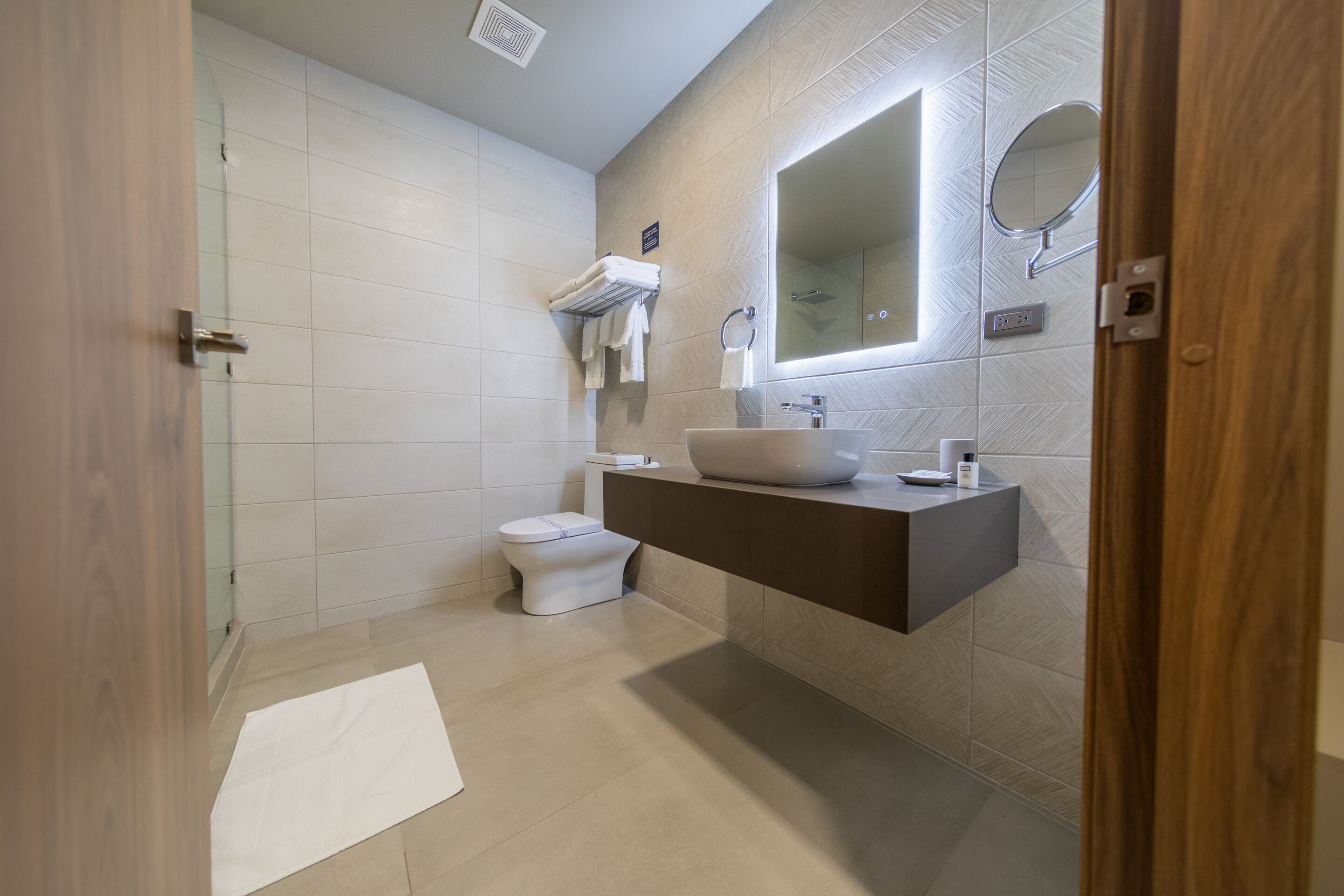 A modern bathroom with a toilet, sink, and mirror.