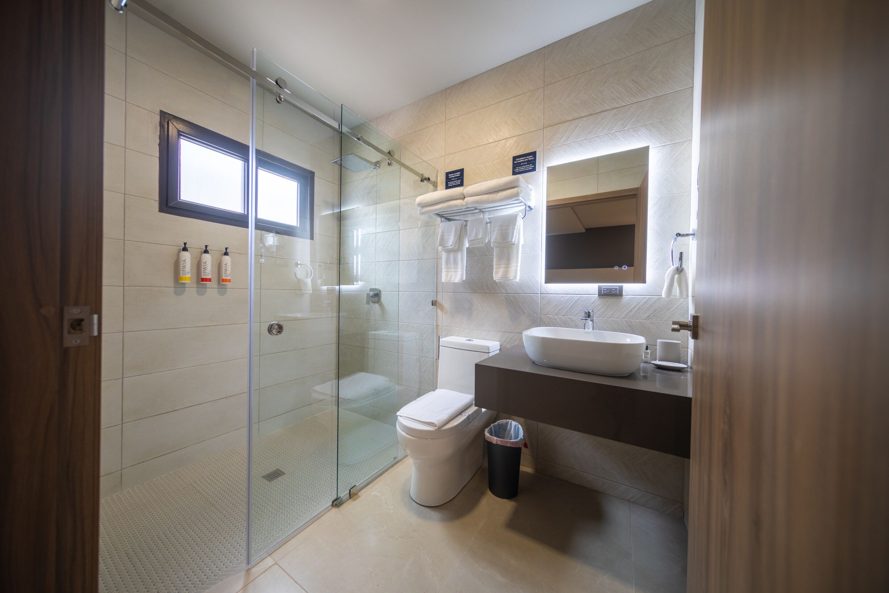 A modern bathroom with a glass-enclosed shower, a toilet, a sink, and a mirror.