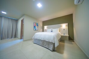 A modern hotel room with a large bed, bedside tables, and a painting on the wall.