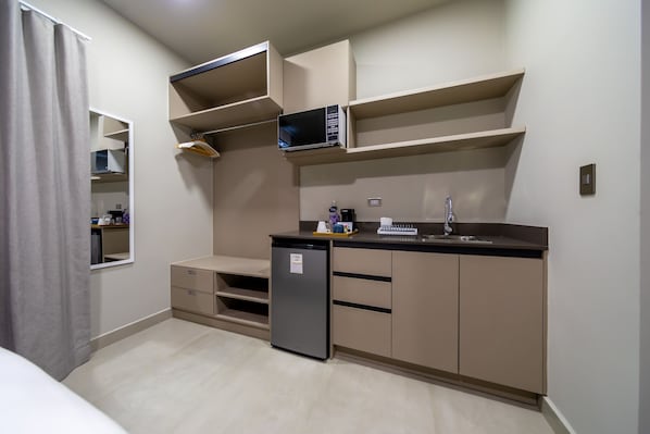 A compact kitchen with built-in appliances, a microwave, and a sink. - Cedrela (Comayagua)