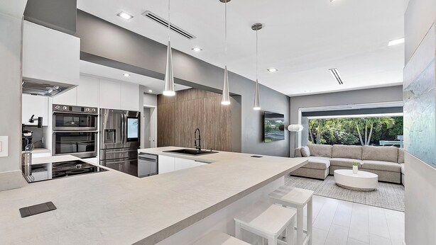 Una cocina moderna con una isla grande, electrodomésticos integrados e iluminación colgante.
